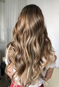 Woman with dark blonde balayaged hair styled in loose mermaid waves